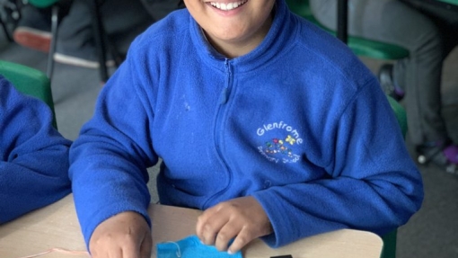 Pupil learning to sew and smiling proudly 