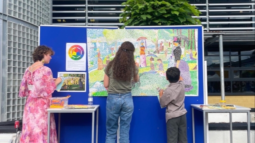 Interactive art installation: three people stand looking at a large board outside. 