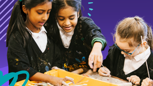 Three young girls paint around a table