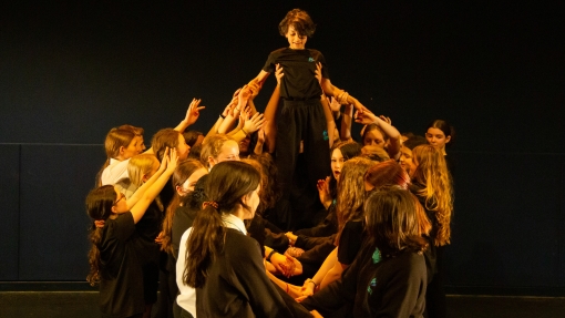 Creative learning at Chorlton High School. A group of young people in a group, holding up someone in the middle. 