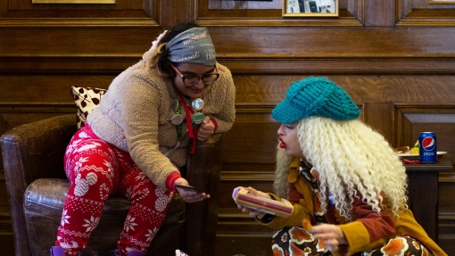 Two people sitting on chairs and looking at a phone and a document.