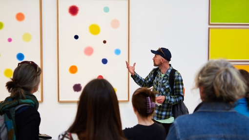 A group of people in a gallery looking at a piece of art work.