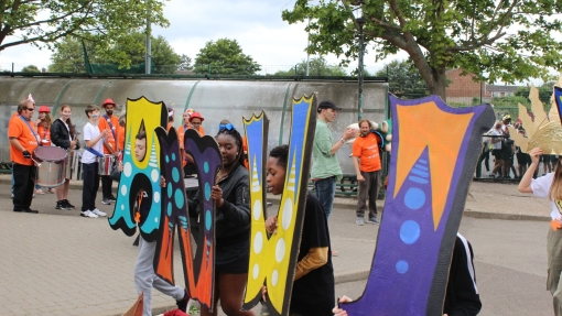 People standing outside holding up large painted letters.