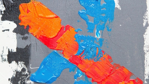 Close-up of an abstract painting with a textured gray background and bold strokes of blue and orange paint. Blue overlaps orange in places, with white and black patches near the edges.