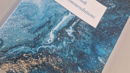 A book with a blue tie dye cover that says Book recommendations. 