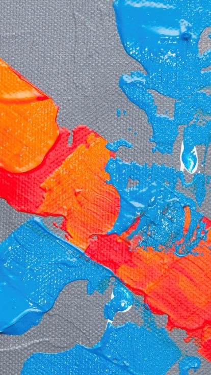 Close-up of an abstract painting with a textured gray background and bold strokes of blue and orange paint. Blue overlaps orange in places, with white and black patches near the edges.