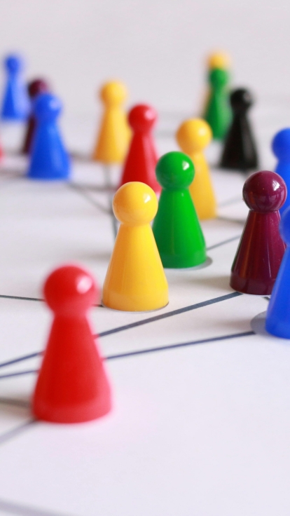 Colorful game pieces connected by lines on a white surface, arranged to suggest a network or relationships. Pieces are red, yellow, green, blue, and purple