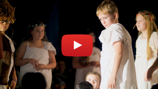 Young children in a play looking intense. There is a YouTube icon overlaid on the image