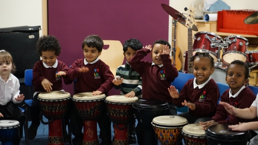 primary school children sitting, playing drums