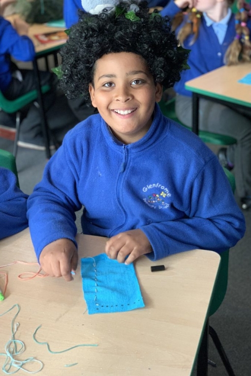 Pupil learning to sew and smiling proudly 