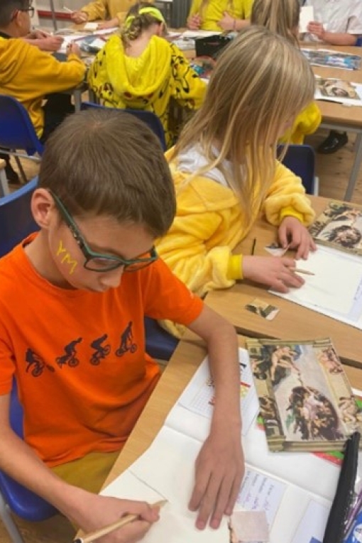 A young boy sits down at a desk, concentrating on the piece of paper in front of him. He is drawing a copy of Michelangelo’s painting of, ‘Adam and God'.