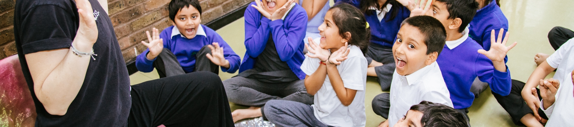 Animated storyteller facing a group of young pupils who have very excited facial expressions
