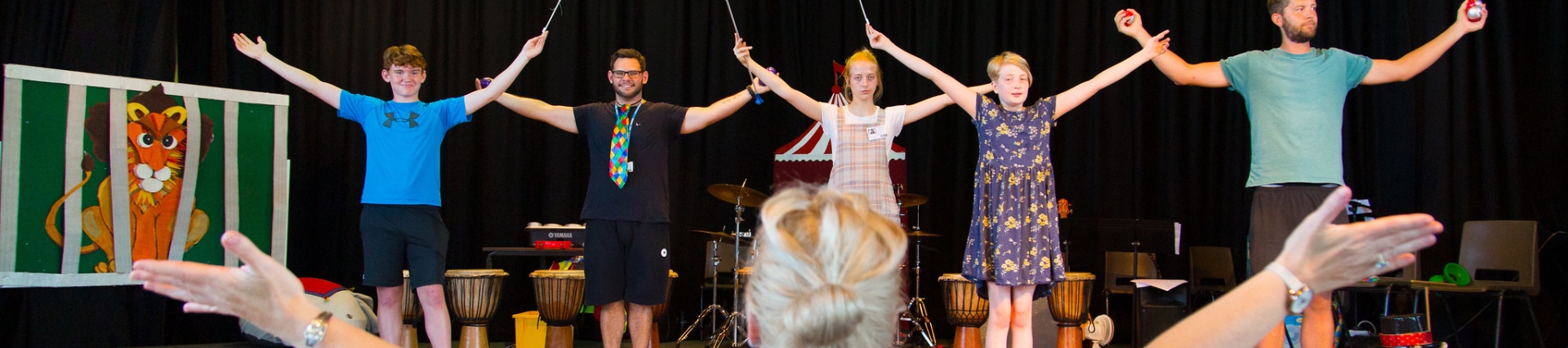 Males dancing on stage with teacher in foreground directing them