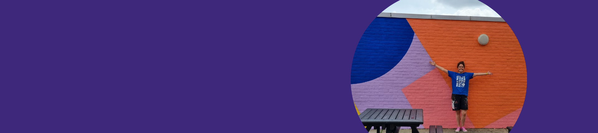 A purple banner with an image on the right of a woman with her arms spread against a vibrant mural on a wall