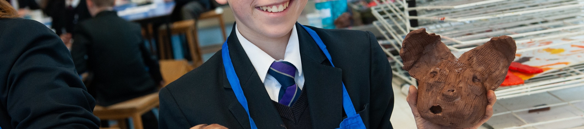 Male student proudly holds up pottery creatures