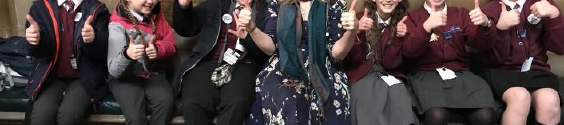 A group of students sitting Parliament with their teacher holding their thumbs up