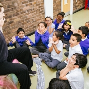 Animated storyteller facing a group of young pupils who have very excited facial expressions