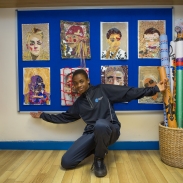 Young male with arms open, displaying his visual art work