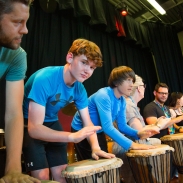 Students playing bongos in a row on stage 