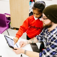 Male pupil and teacher looking at a tablet screen 