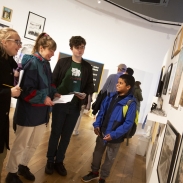 Four young people in a row, discussing art work on display on the wall in front of them