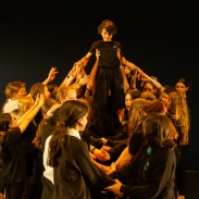 Creative learning at Chorlton High School. A group of young people in a group, holding up someone in the middle. 