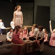 A group of young people stand on a stage acting