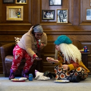 Two people sitting on chairs and looking at a phone and a document.
