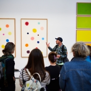 A group of people in a gallery looking at a piece of art work.