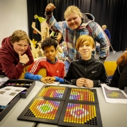 Young people looking happy in front of a table of beaded art work