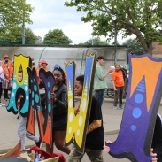 People standing outside holding up large painted letters.