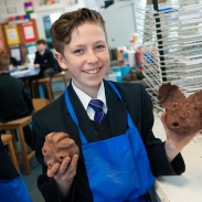 Male student proudly holds up pottery creatures
