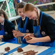 Girls making clay models and smiling