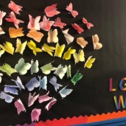 Paper origami diplayed as a heart on a black wall with LGBT written next to it