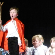 A young boy in a regal outfit performing on stage 