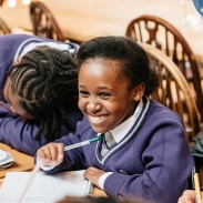 Young female pupil smiling and writing at a First Story workshop in Oxford