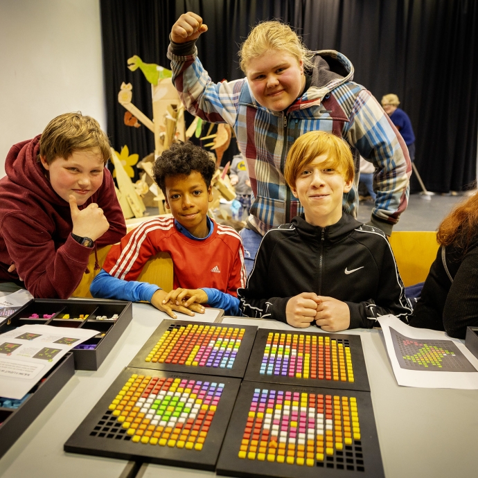 Young people looking happy in front of a table of beaded art work